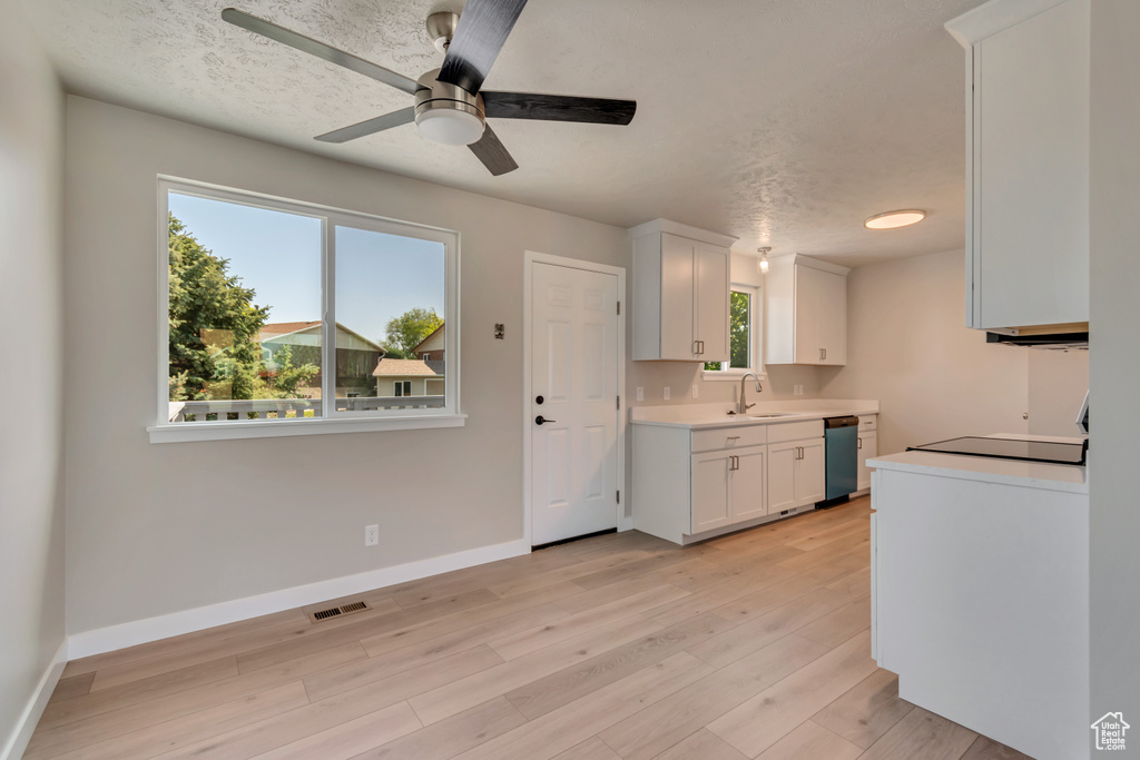 Kitchen with light countertops, ceiling fan, light wood-style flooring, white cabinets, and dishwasher