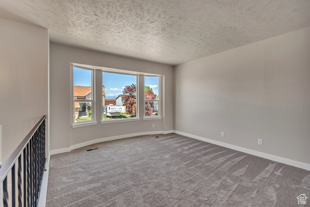 Unfurnished room featuring a textured ceiling and carpet floors
