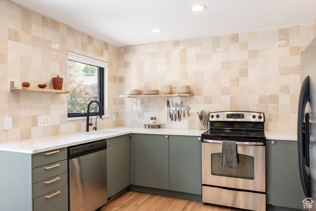 Kitchen featuring appliances with stainless steel finishes, open shelves, tasteful backsplash, light countertops, and recessed lighting