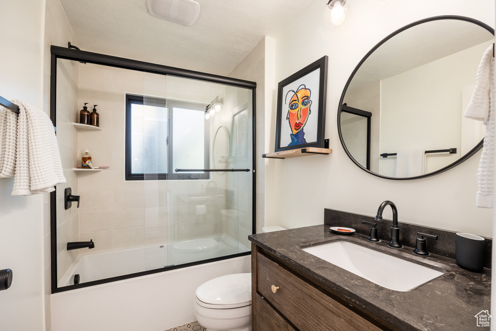 Full bath featuring vanity and shower / bath combination with glass door