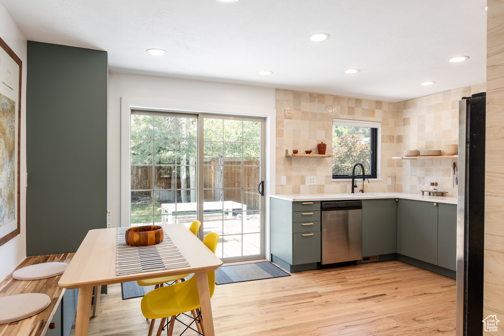 Kitchen featuring gray cabinetry, stainless steel appliances, open shelves, light countertops, and light wood finished floors