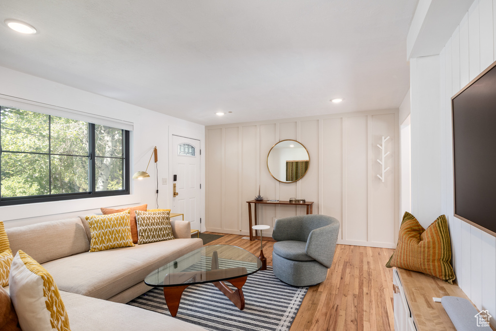 Living area with a decorative wall, light wood-style floors, and recessed lighting