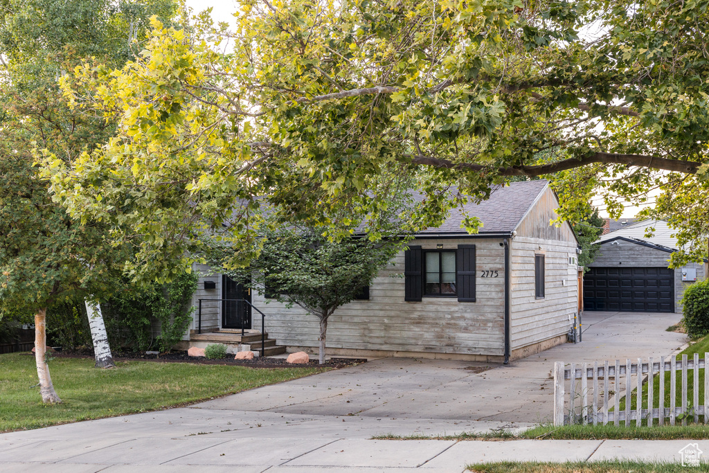 View of front of home featuring an outbuilding, a detached garage, and a shingled roof