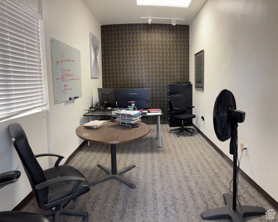 Carpeted office featuring baseboards and an accent wall