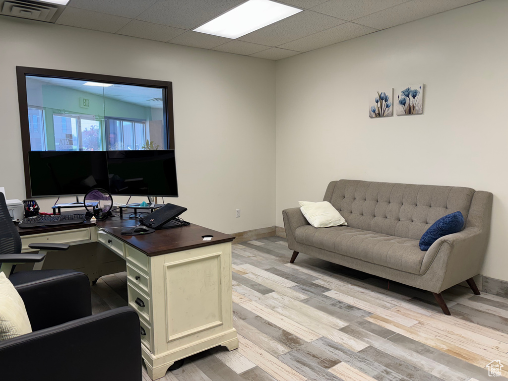 Home office with light wood finished floors and a paneled ceiling