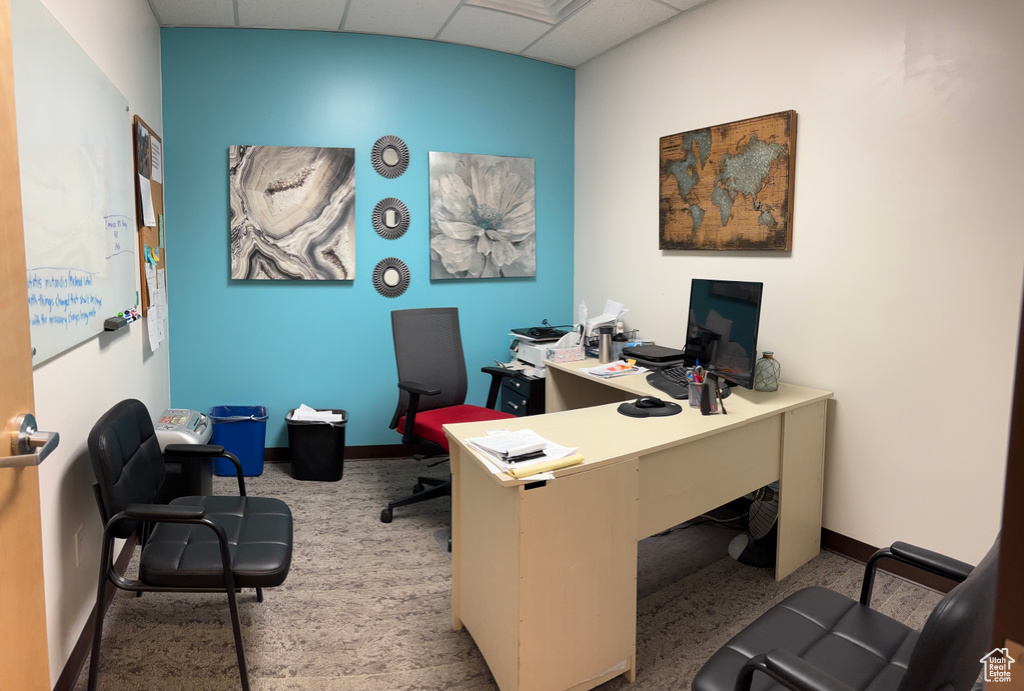 Carpeted office featuring a drop ceiling and baseboards