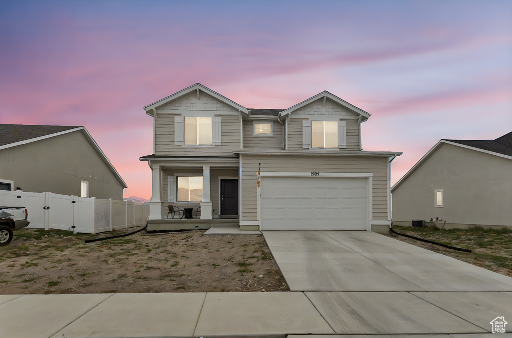 View of front of property featuring a porch, a garage, and driveway