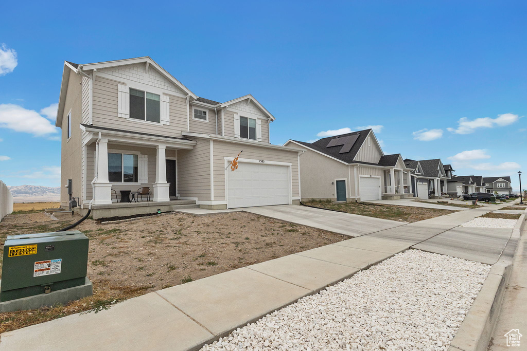 View of front of home with covered porch, driveway, a garage, and a residential view