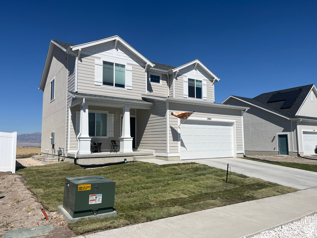 View of front of home featuring a porch, concrete driveway, a front lawn, and an attached garage