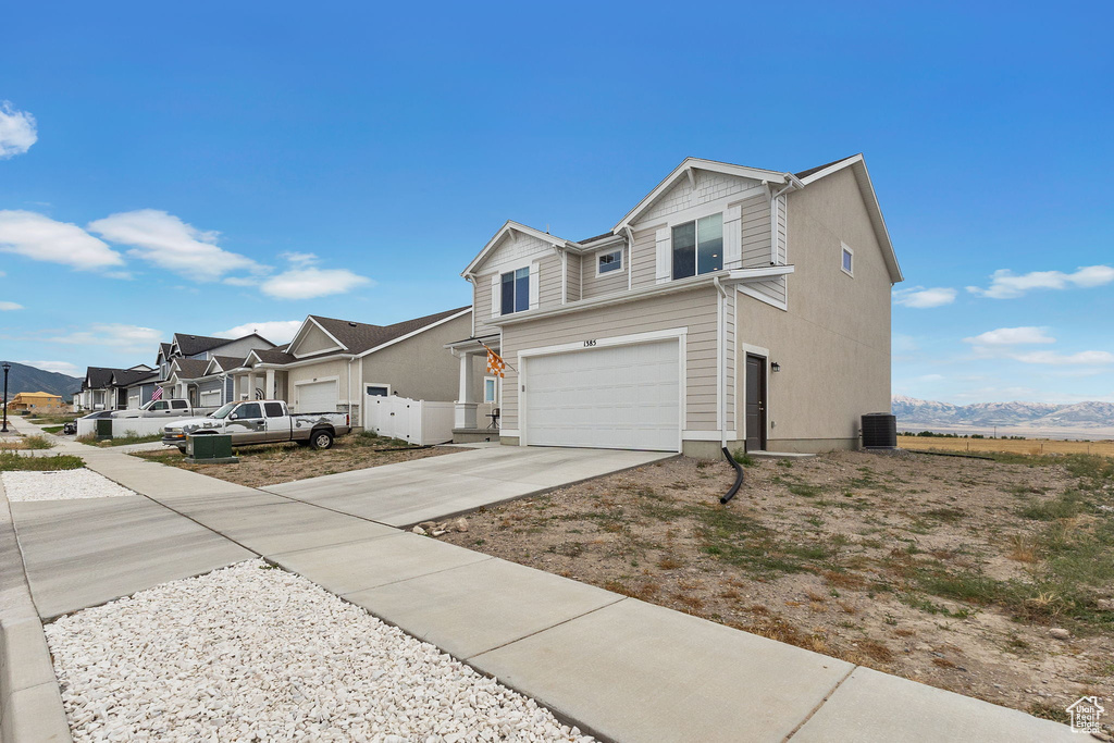 View of front of house featuring concrete driveway, an attached garage, a residential view, and a mountain view