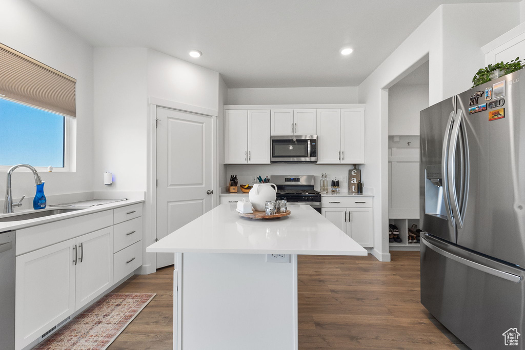 Kitchen featuring stainless steel appliances, white cabinets, a center island, dark wood finished floors, and recessed lighting
