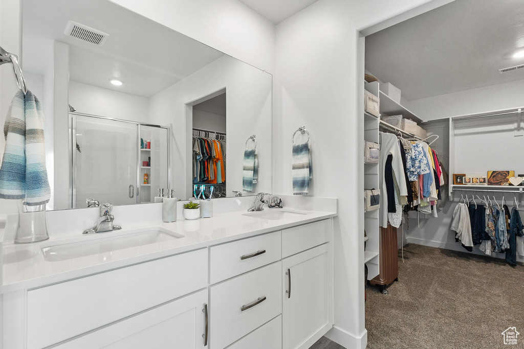 Bathroom featuring a spacious closet, double vanity, a stall shower, and recessed lighting