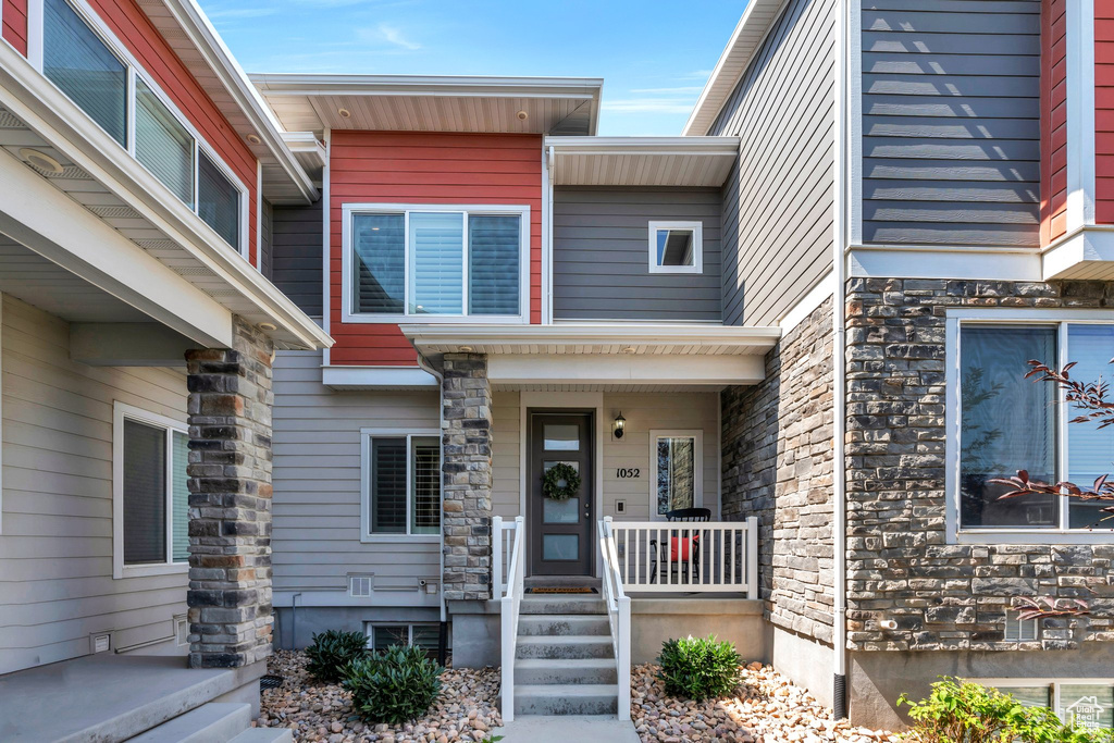 Entrance to property featuring stone siding and covered porch