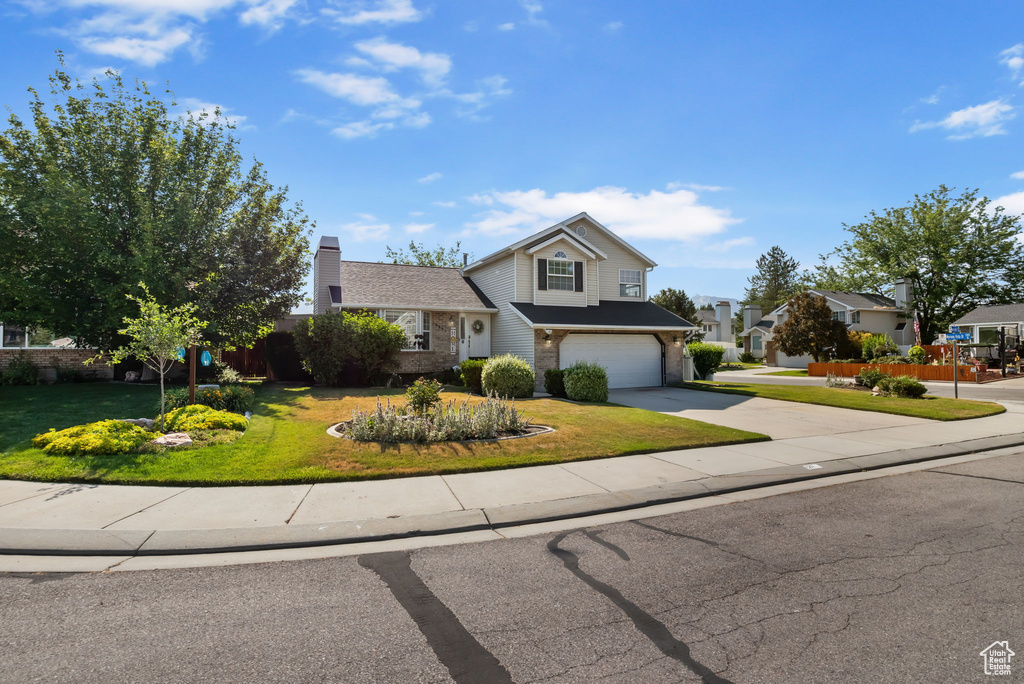 View of front of home featuring concrete driveway, a garage, a front lawn, and brick siding