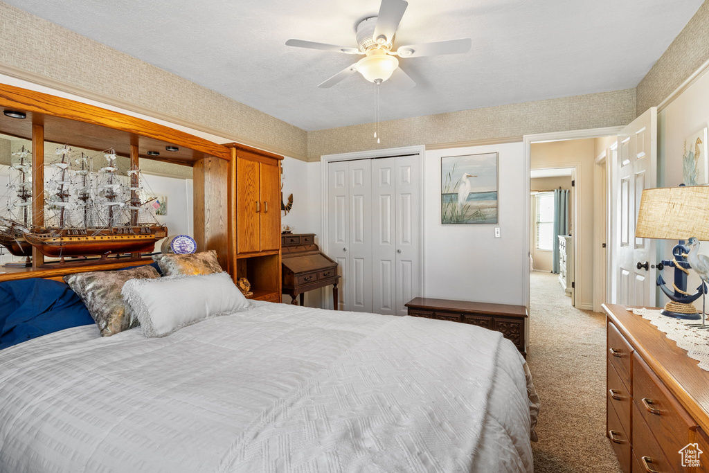Bedroom with light colored carpet, a closet, and a ceiling fan