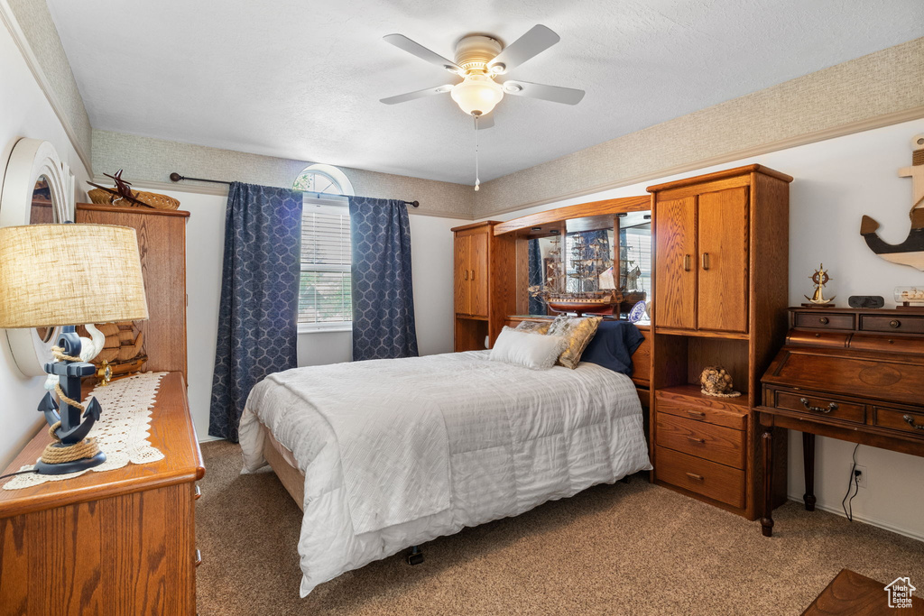 Carpeted bedroom with a ceiling fan