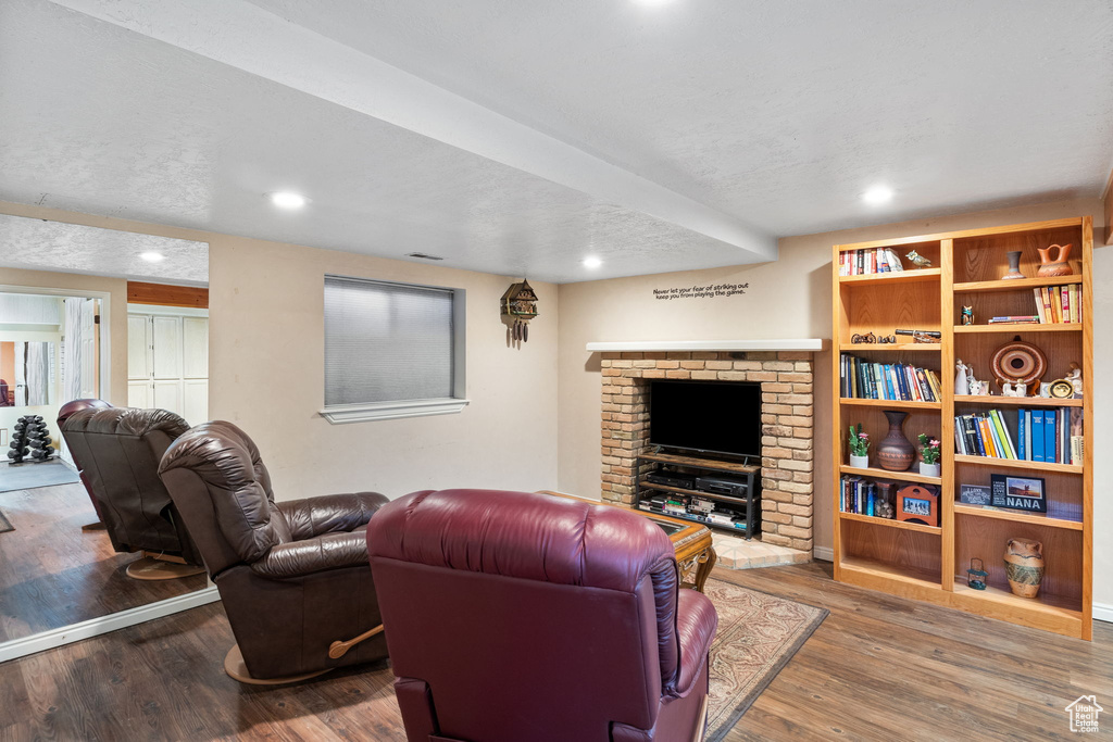 Living room with wood finished floors, recessed lighting, and a fireplace