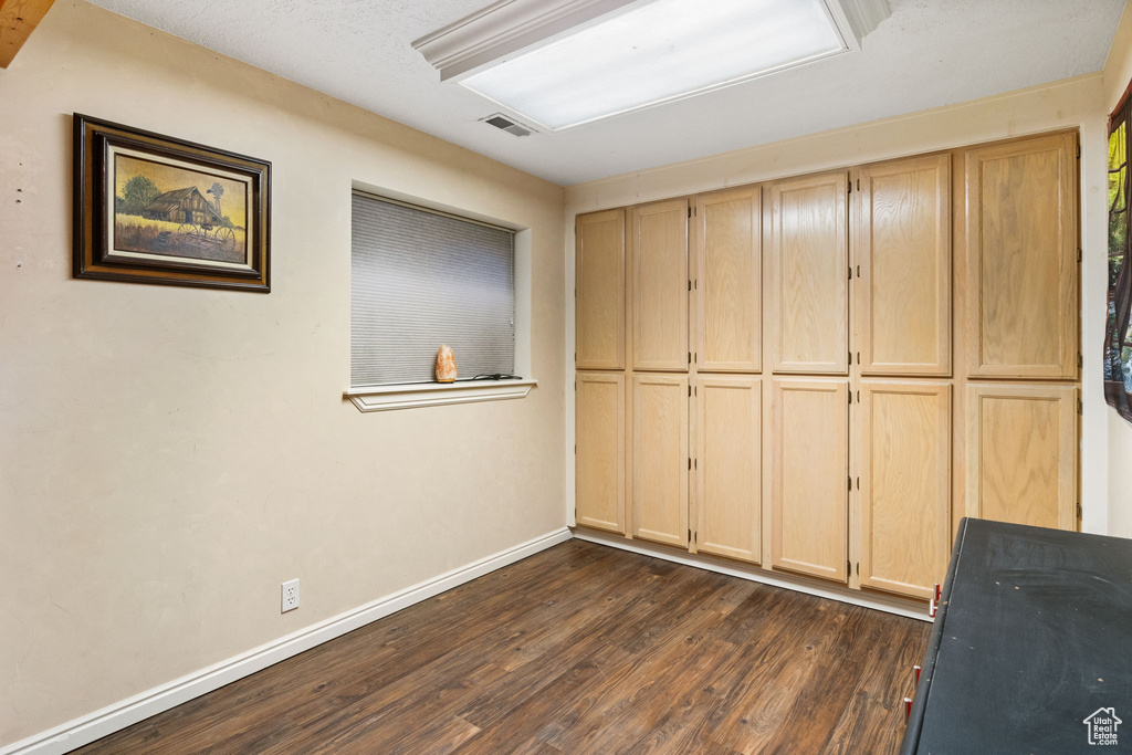 Unfurnished bedroom featuring dark wood-style floors and baseboards
