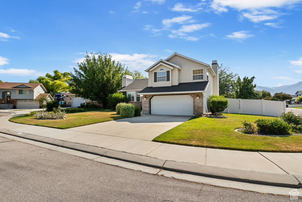 Traditional-style home featuring a chimney, an attached garage, driveway, and brick siding