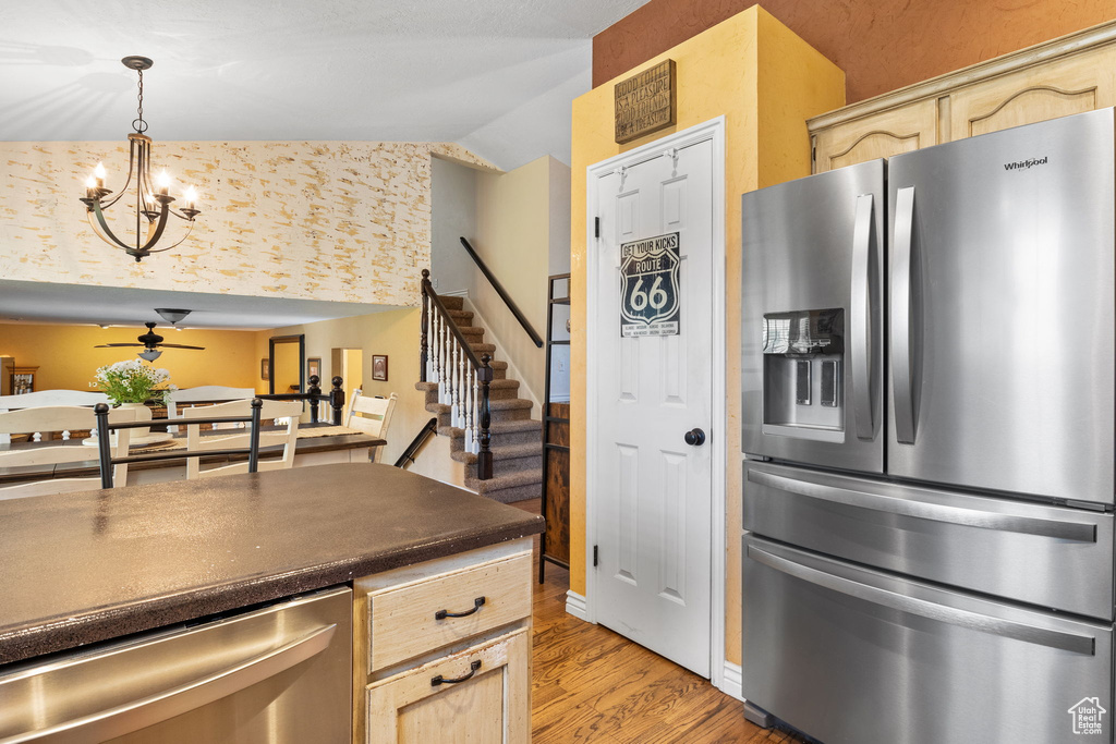 Kitchen with stainless steel appliances, light wood finished floors, light brown cabinetry, a ceiling fan, and vaulted ceiling