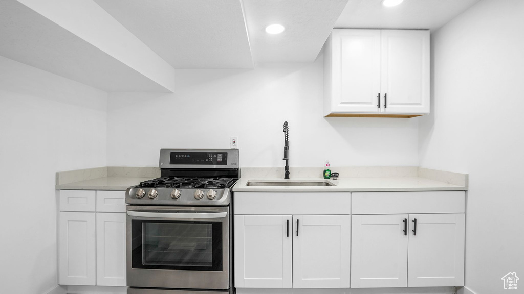 Kitchen with stainless steel gas range, white cabinets, light countertops, and recessed lighting