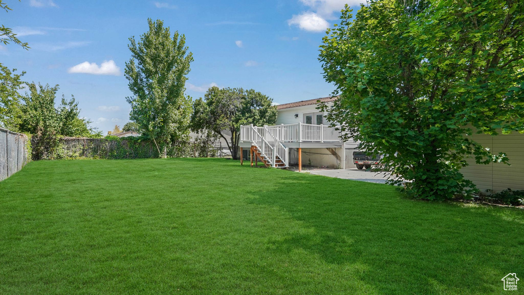 Fenced backyard featuring a deck, stairs, and a patio