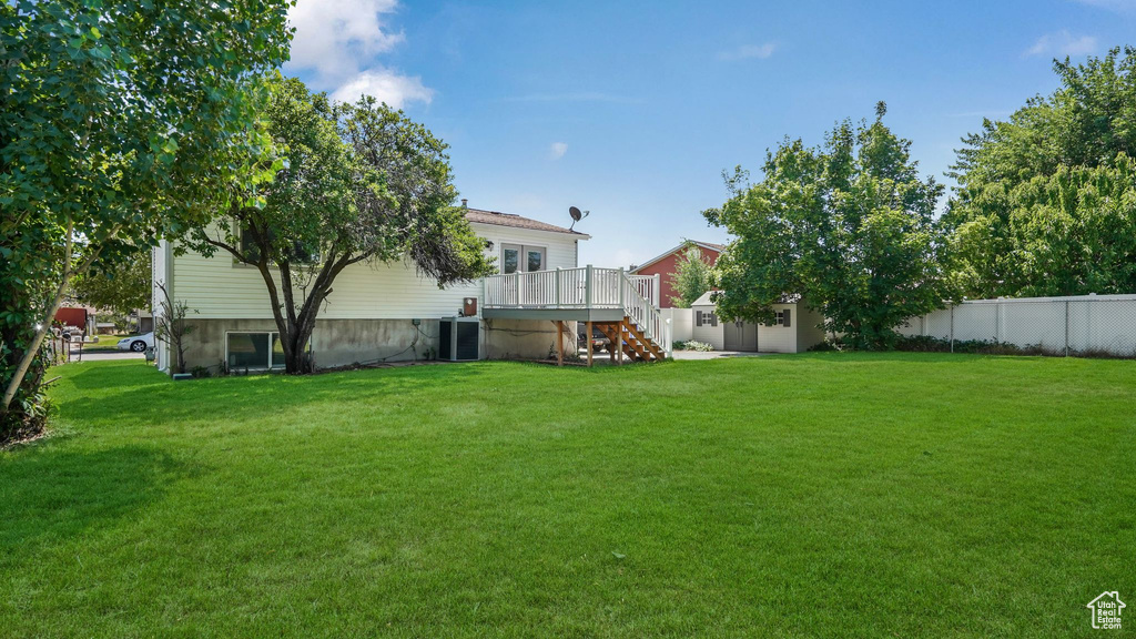 View of yard featuring stairs, a storage shed, and a deck