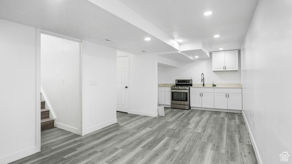 Kitchen featuring stainless steel range, recessed lighting, light wood finished floors, white cabinets, and light countertops