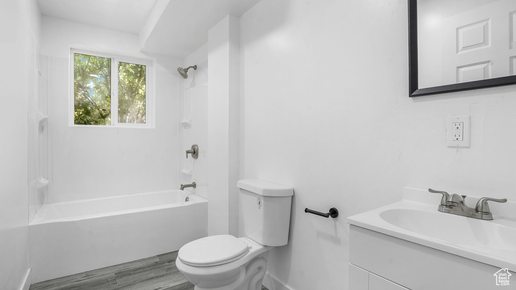 Full bath with washtub / shower combination, vanity, and wood finished floors