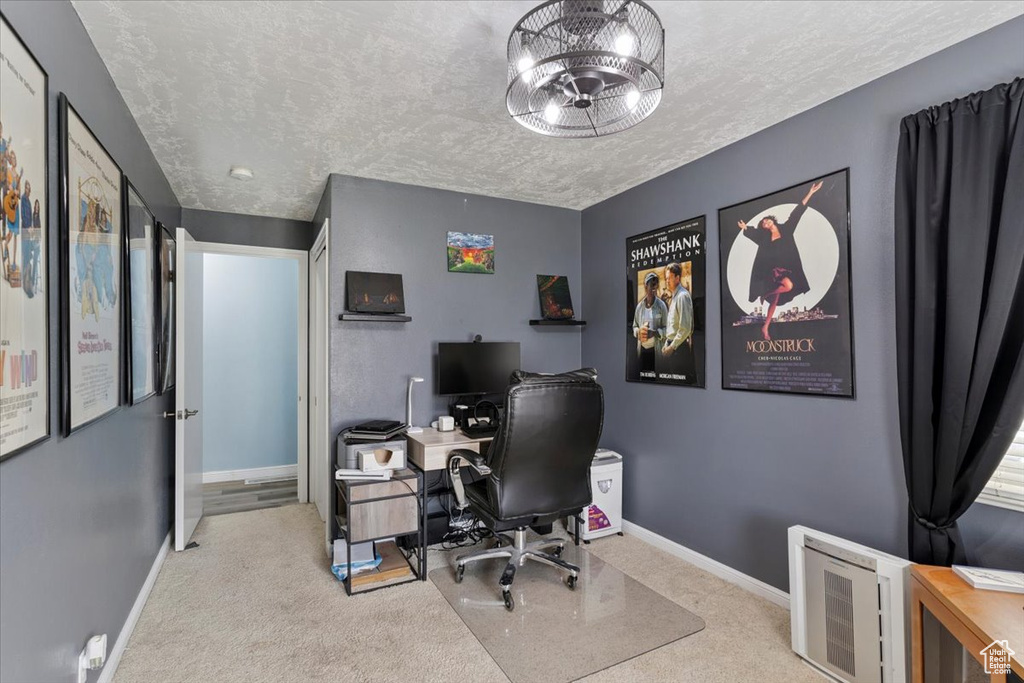 Carpeted home office featuring baseboards and a textured ceiling