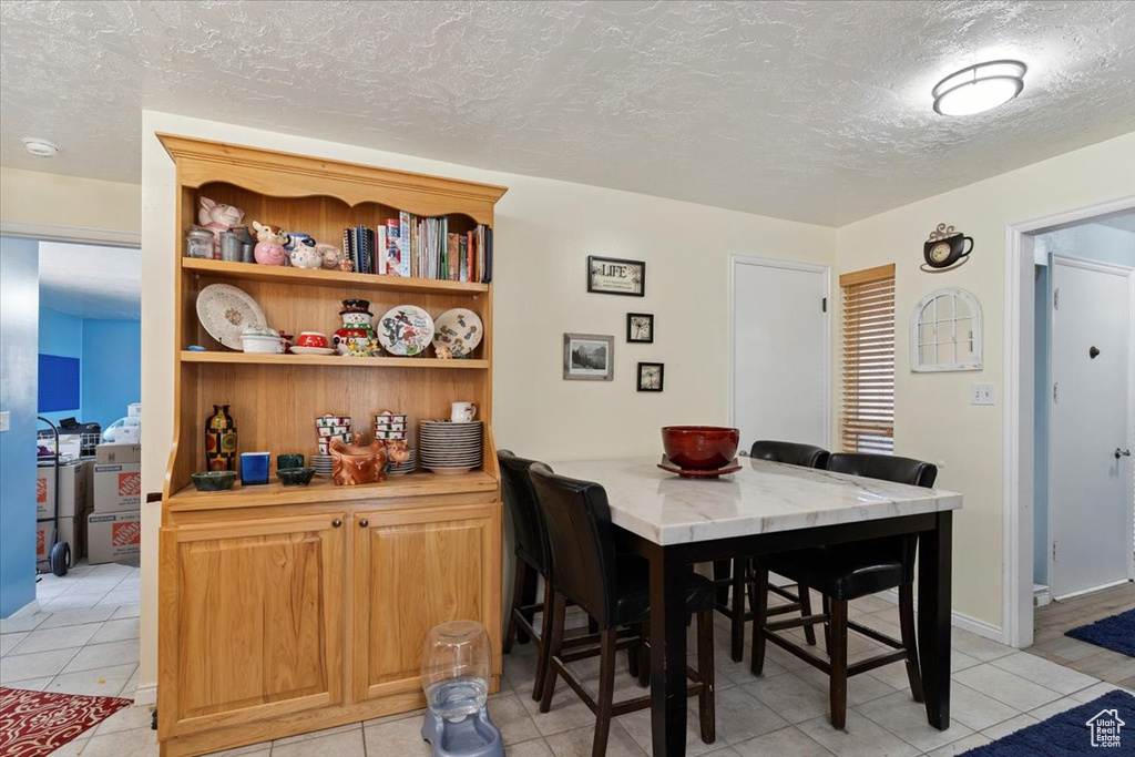 Dining space with light tile patterned floors and a textured ceiling