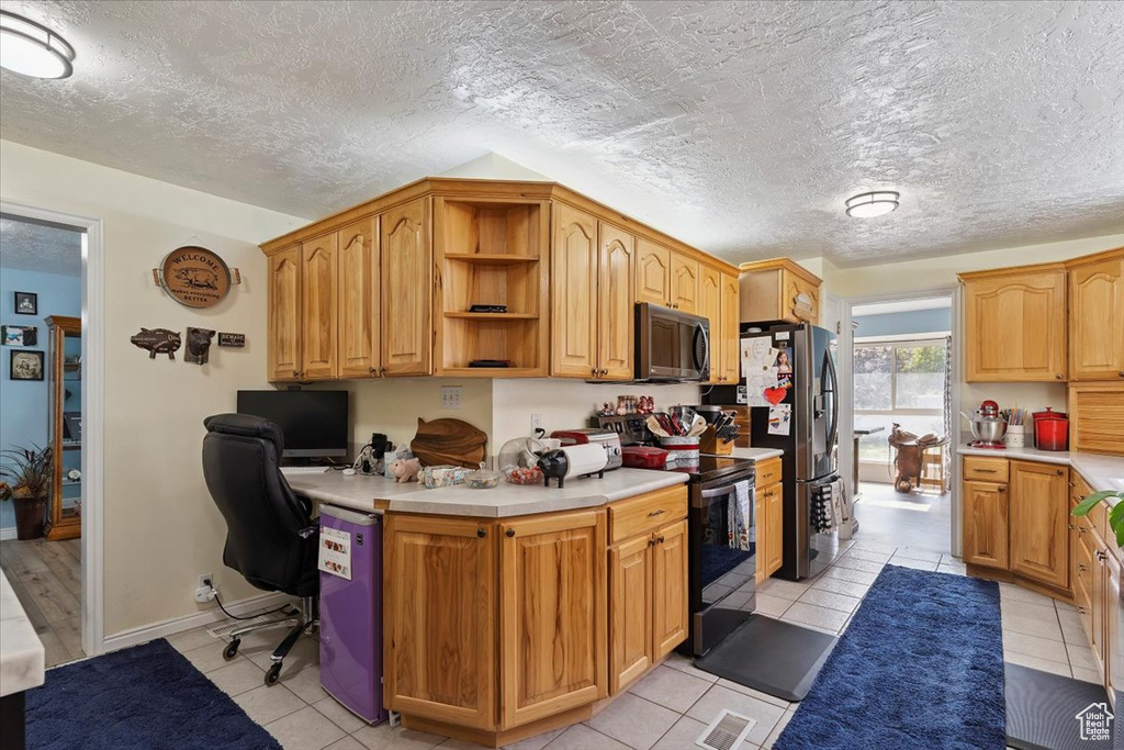 Kitchen with black appliances, light tile patterned flooring, light countertops, open shelves, and a textured ceiling