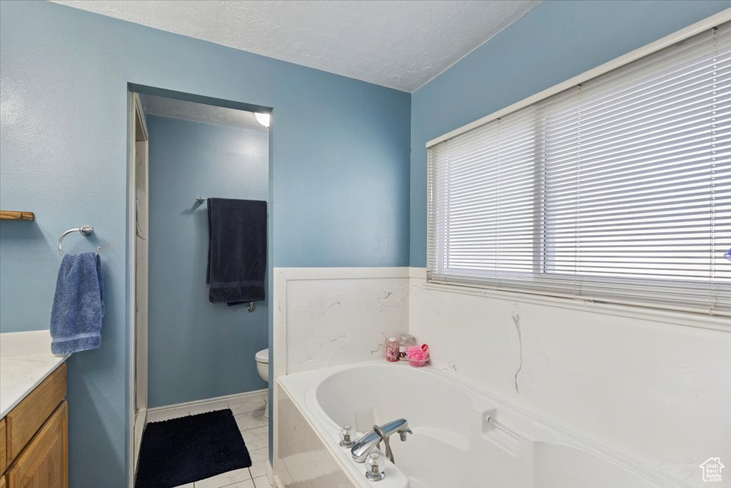 Full bath with vanity, a bath, a textured ceiling, and tile patterned floors