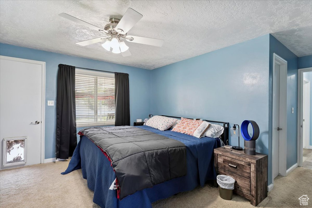 Carpeted bedroom featuring a textured ceiling and ceiling fan