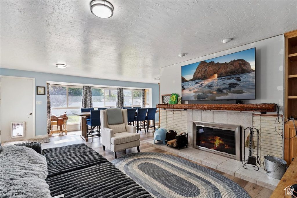 Living area featuring a fireplace, a textured ceiling, and wood finished floors