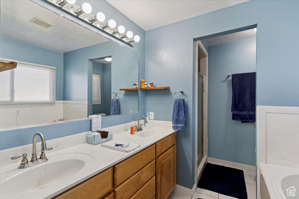 Full bath featuring a garden tub, double vanity, tile patterned floors, and a shower stall