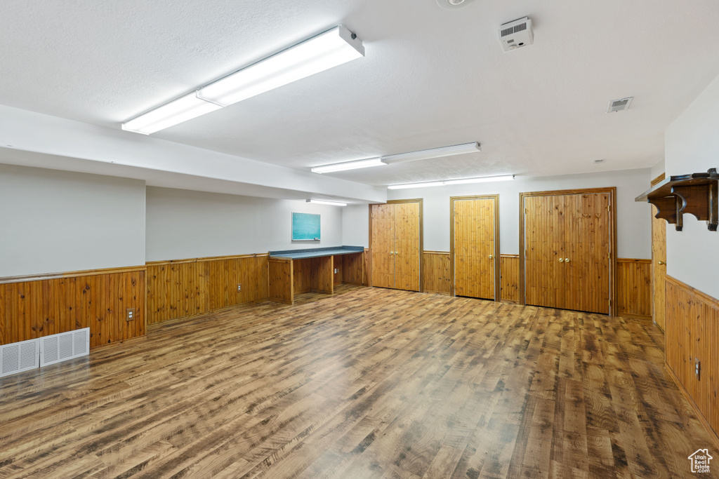 Below grade area featuring a wainscoted wall, wood walls, and wood finished floors