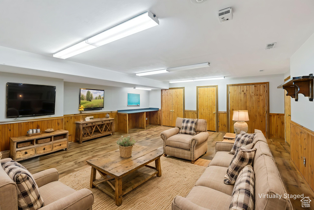 Living area with wainscoting, wood walls, and light wood-type flooring