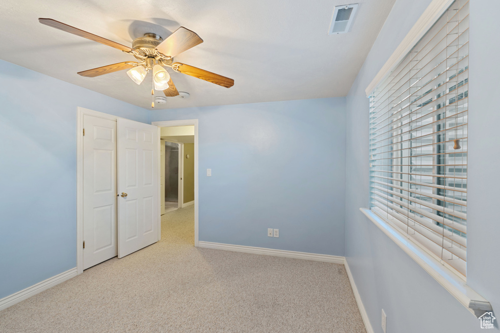 Carpeted empty room featuring baseboards and a ceiling fan