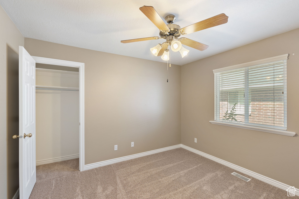 Unfurnished bedroom featuring carpet flooring, a closet, and ceiling fan