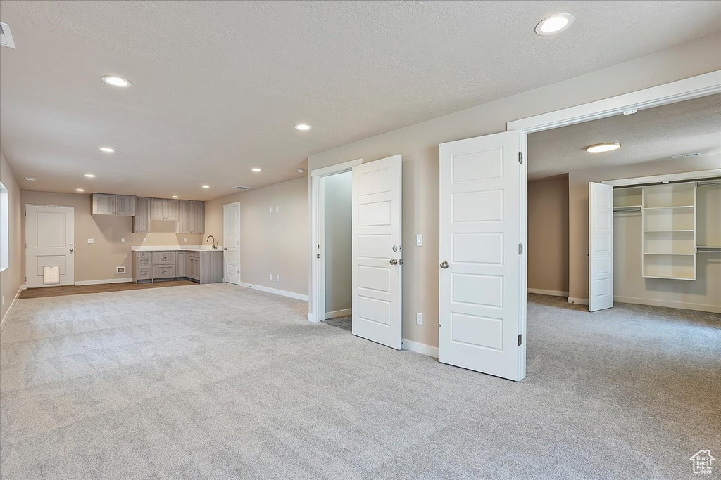 Unfurnished living room with light colored carpet and recessed lighting