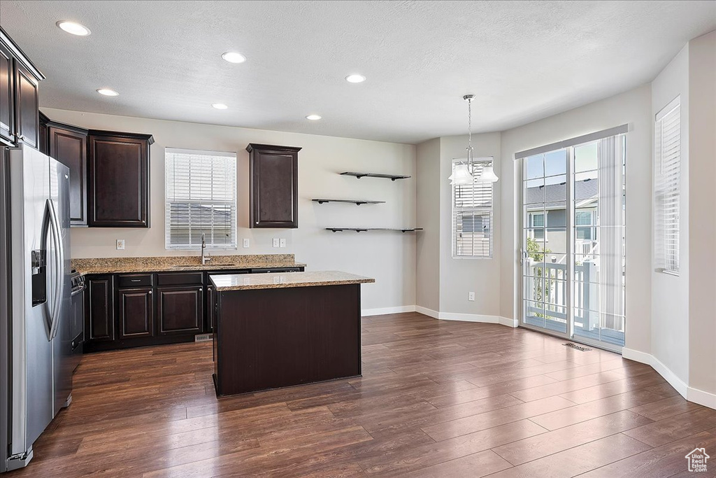 Kitchen with stainless steel fridge with ice dispenser, a center island, dark brown cabinetry, dark wood finished floors, and recessed lighting