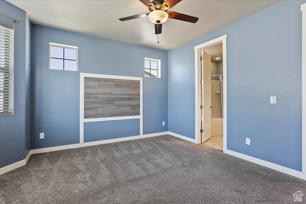 Carpeted spare room with a ceiling fan and baseboards