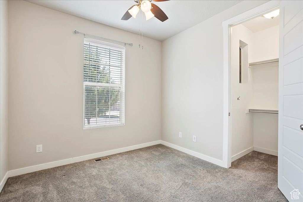 Unfurnished bedroom featuring carpet, a walk in closet, a closet, and ceiling fan