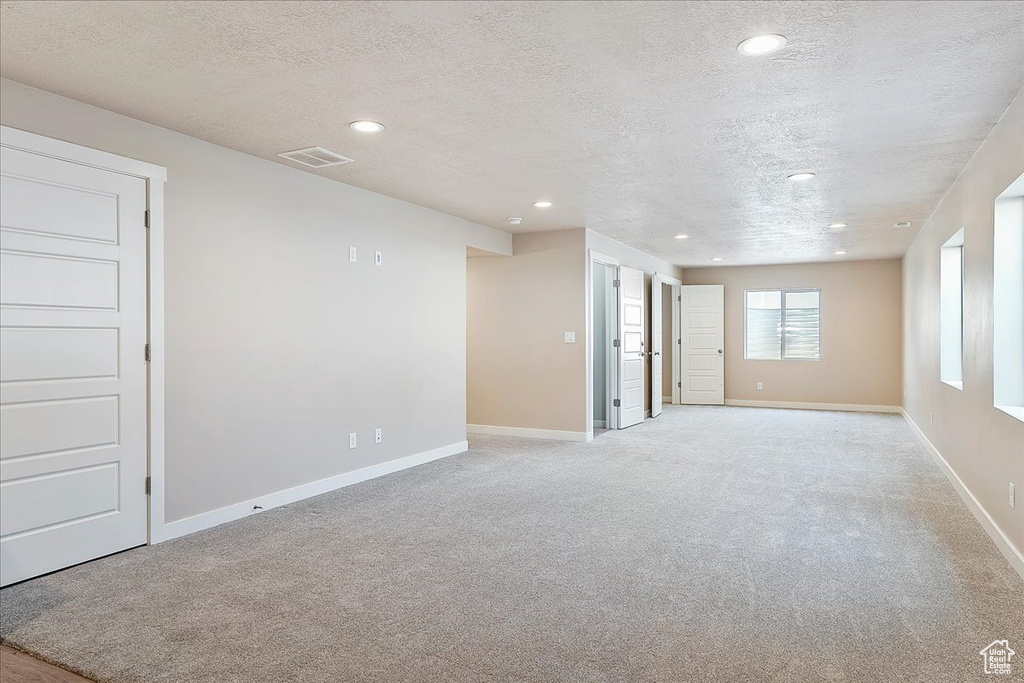 Spare room featuring a textured ceiling, recessed lighting, and light colored carpet