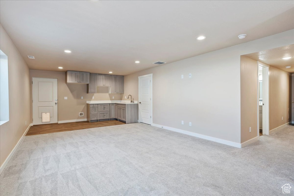 Unfurnished living room with light colored carpet and recessed lighting