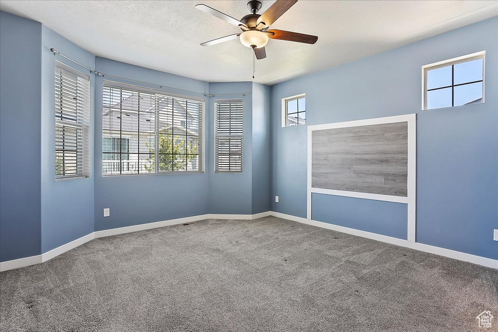 Carpeted empty room with ceiling fan and baseboards