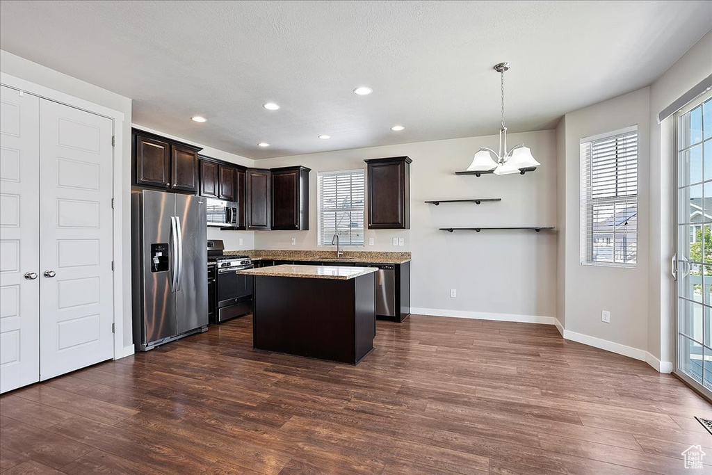 Kitchen with appliances with stainless steel finishes, dark brown cabinetry, dark wood-type flooring, recessed lighting, and plenty of natural light