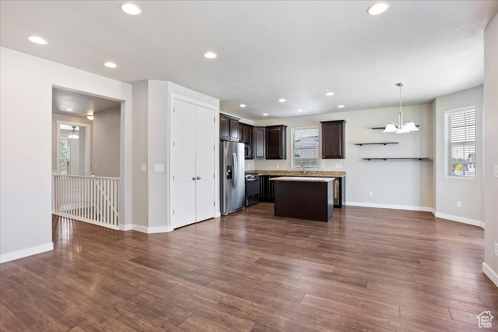 Kitchen with stainless steel fridge, dark brown cabinetry, stove, a center island, and dark wood-type flooring