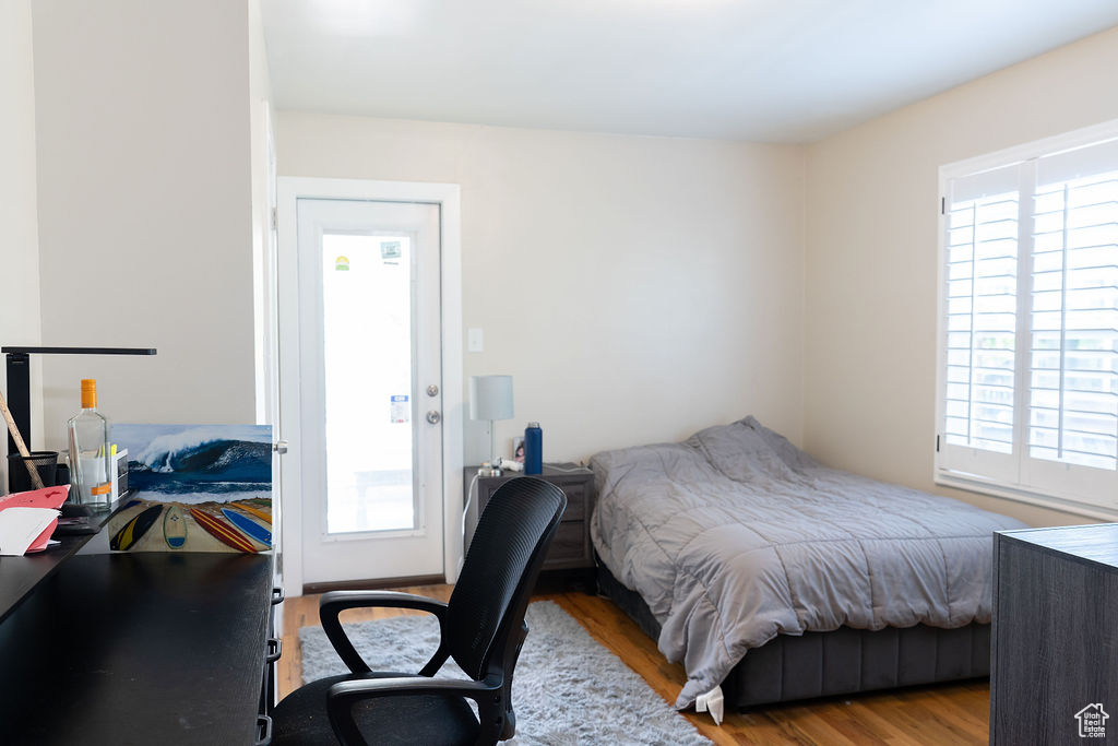 Bedroom featuring multiple windows, wood finished floors, and an office area